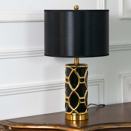 Black ceramic table lamp with black fabric shade and gold lattice detailing creating sophisticated luxury ambient lighting.