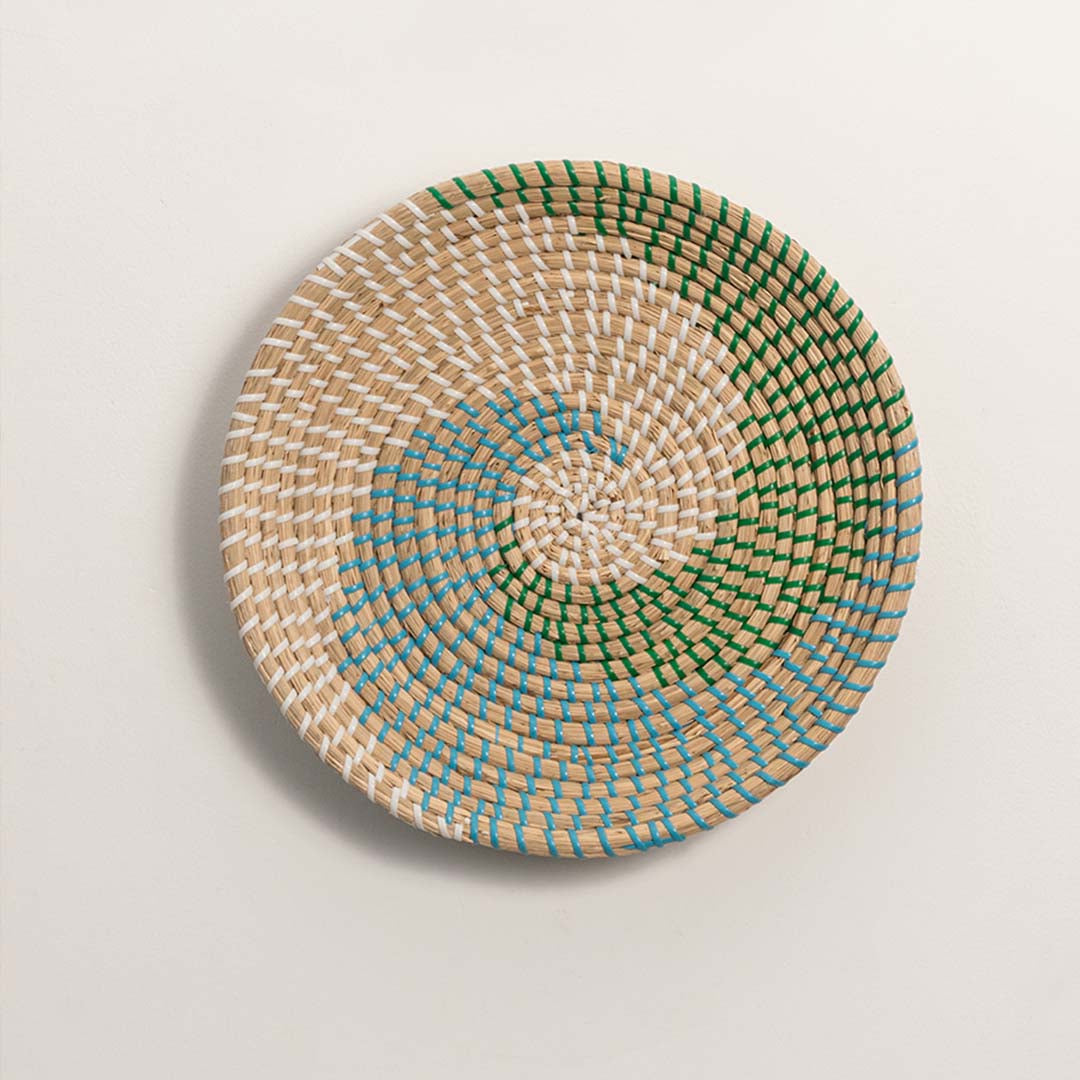 Natural green and terracotta woven decorative wall basket with spiral pattern for artistic wall styling and home decor.