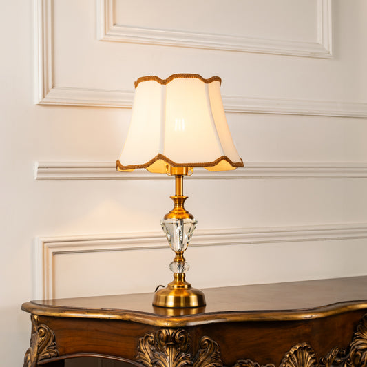Clear crystal table lamp with scalloped fabric shade offering refined classic ambient lighting for elegant home interiors.