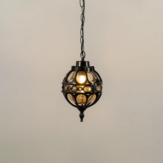Illuminated black metal sphere pendant light with decorative cage design and warm bulb glowing against a plain white background.