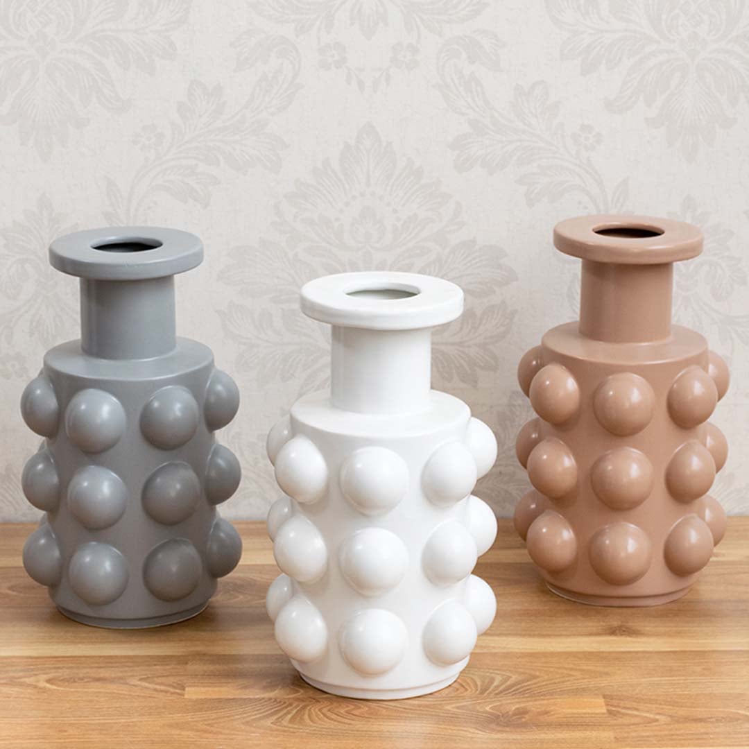 A beige designer vase with sphere accents shown as part of a styled grouped decor setup highlighting its modern statement design for interiors.