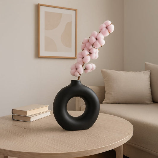 Pink cotton stem preserved artificial flowers styled in black ceramic vase lifestyle decor on wooden coffee table.
