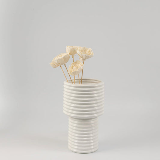 Elegant white flower stick arrangement in a ribbed ceramic vase enhancing modern home decor.
