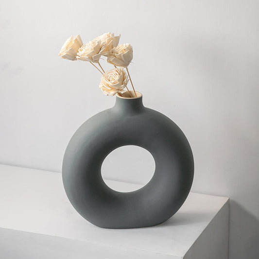 Grey round ceramic vase with hole design styled with white dried flower stems modern home decor accent for table.