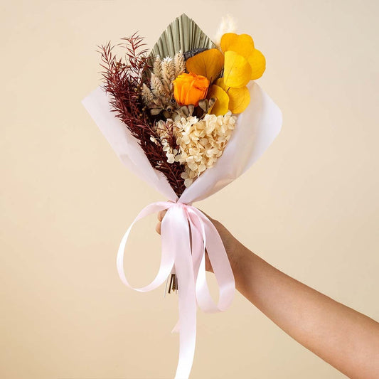Elegant preserved flower bouquet on white background featuring orange infinity rose apple leaves hydrangea and eucalyptus.