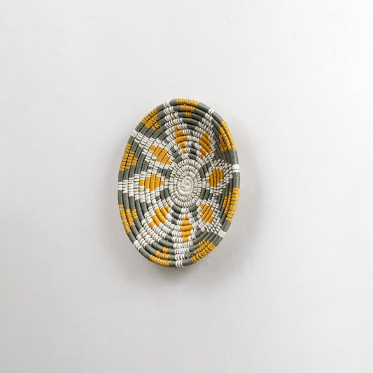 Side angled view of a handcrafted woven wall plate showing its raised textured weaving pattern and natural material detailing.