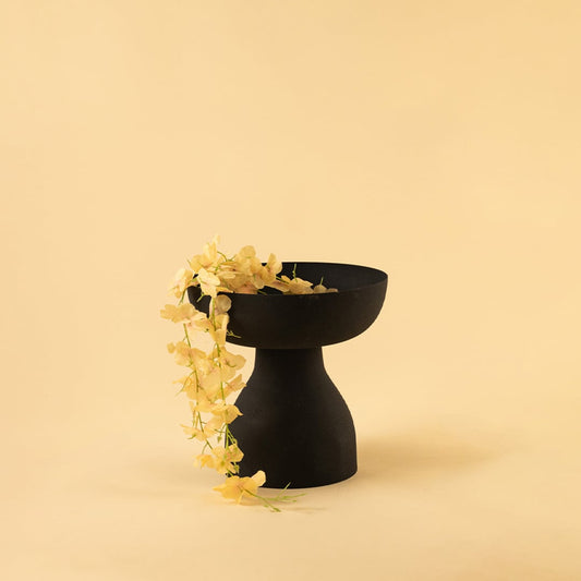 Black pedestal bowl with matte finish styled in a modern living space adding bold sculptural decor to shelves and tables.