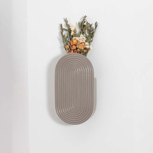 A contemporary oval ceramic wall vase with textured linear grooves shown on a clean white background offering a simple elegant and modern product display.