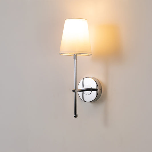 Contemporary wall light in chrome metal finish with fabric shade for bedroom or living room ambient lighting decor white background.