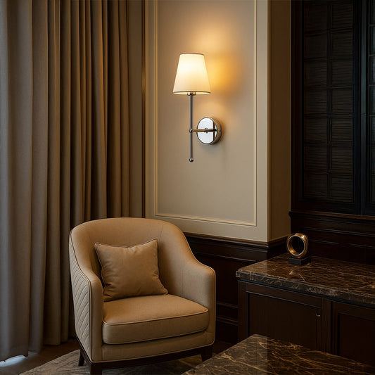 Chrome metal wall light with white fabric shade styled in a modern room creating soft ambient lighting for hallways bedrooms and living areas.