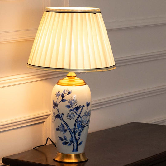 Ceramic table lamp with blue floral detailing and a cream pleated shade providing soft illumination ideal for traditional and modern interiors.