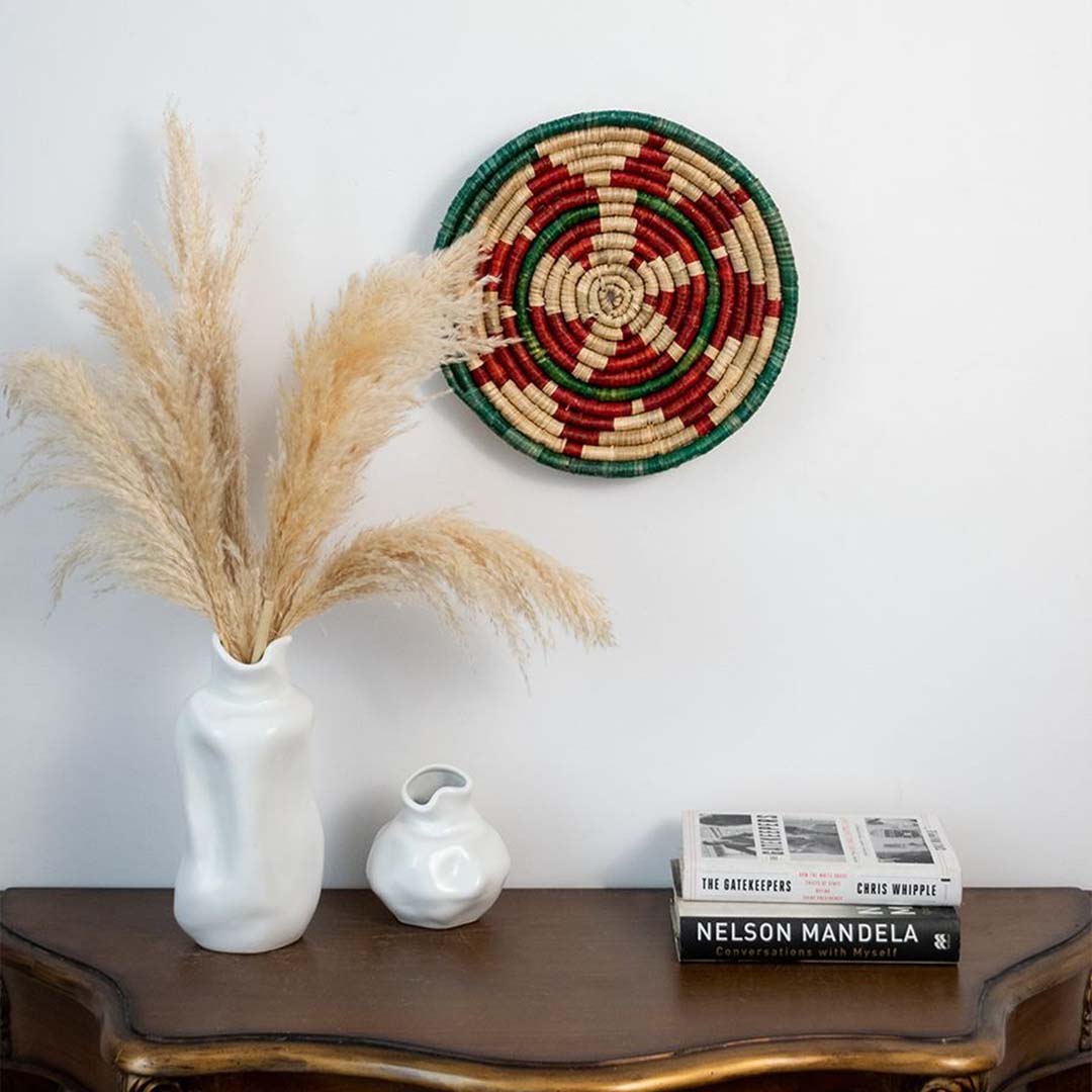 Red and green handwoven sabai grass wall basket styled on interior wall bringing colorful ethnic texture and statement decor appeal.