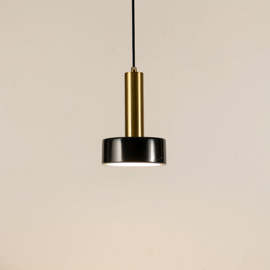 Black marble and metal round base pendant light hanging against plain background with light off for modern luxury décor.