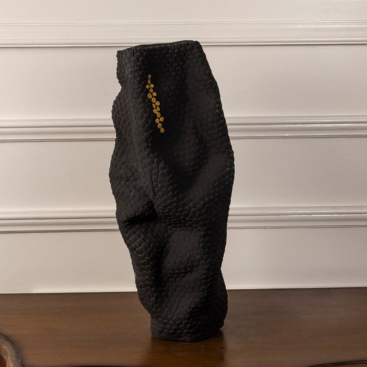 Matte black sculptural ceramic vase with gold accent dots on white background showcasing elegant handcrafted artistry.