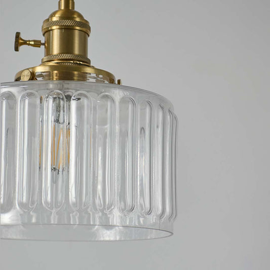 Closeup of ribbed clear glass and brass metal pendant light showcasing premium texture and craftsmanship.