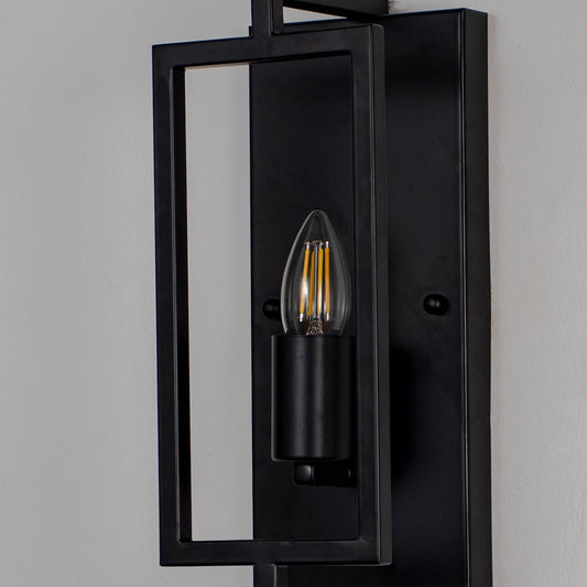 Closeup of wall lamp with sleek black rectangular metal frame and exposed bulb showcasing modern industrial design.
