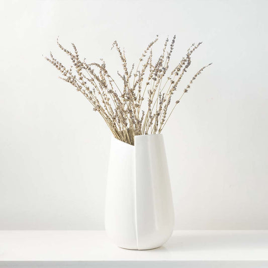 Minimal white ceramic vase placed on a clean pedestal in a bright modern setting adding a soft contemporary touch to the lifestyle space.