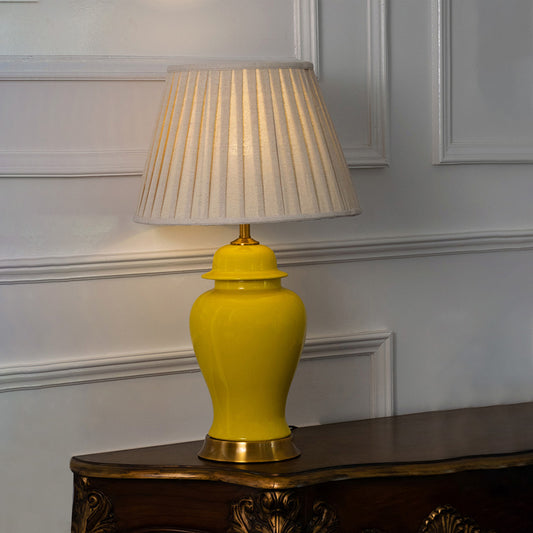 Yellow ceramic table lamp with pleated fabric shade adding timeless traditional style and warm ambient lighting indoors.