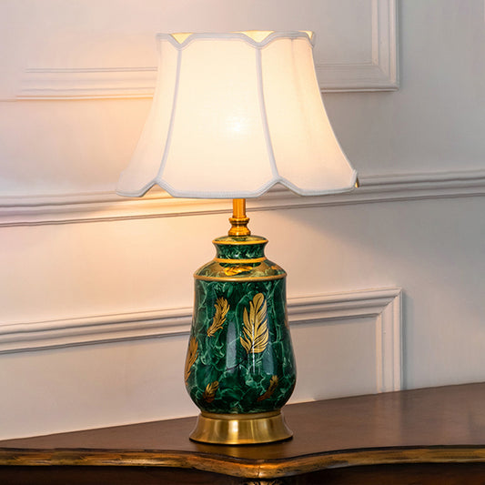Green ceramic table lamp with fabric shade styled on a wooden console table creating warm traditional ambient lighting.