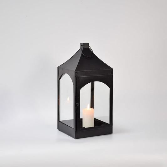 Black metal and glass lantern with candle unlit on white background highlighting solid frame clean edges and modern lantern design.