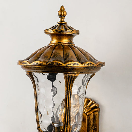 Closeup of antique gold outdoor lantern showing curved detailing and textured glass for elegant vintage outdoor lighting.
