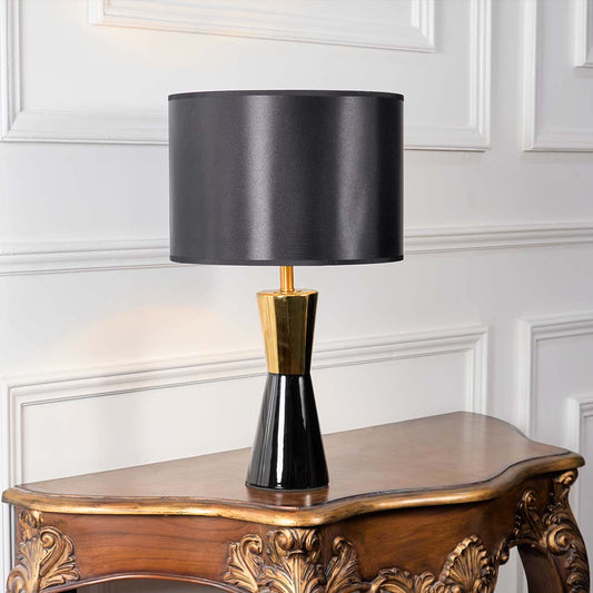 Black fabric shade table lamp with gold metal stem and dark ceramic base for modern luxury interior decor.