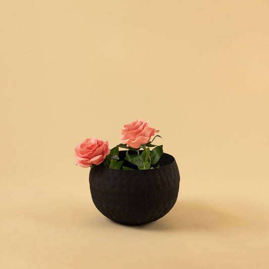 Small textured black rounded metal bowl with pink flowers for modern home decor and chic tabletop accent display.