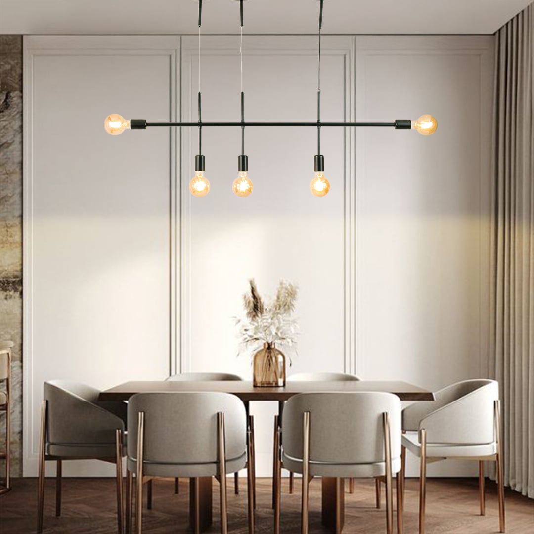 Black metal linear chandelier with exposed globe bulbs styled in a modern interior adding warm ambient lighting to the room.