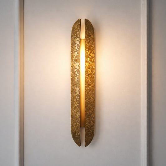 Contemporary gold wall sconce with glowing textured glass cylinder on neutral wall background ideal for elegant bedroom or hallway lighting.