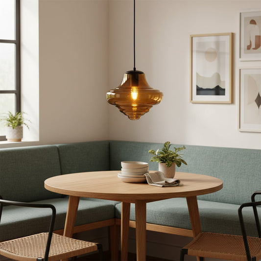 Amber glass pendant light with metal fitting hanging above round dining table creating warm glow and inviting modern dining space.