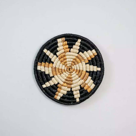 Handwoven seagrass round wall basket decor in natural beige and black with floral star woven pattern on white background.