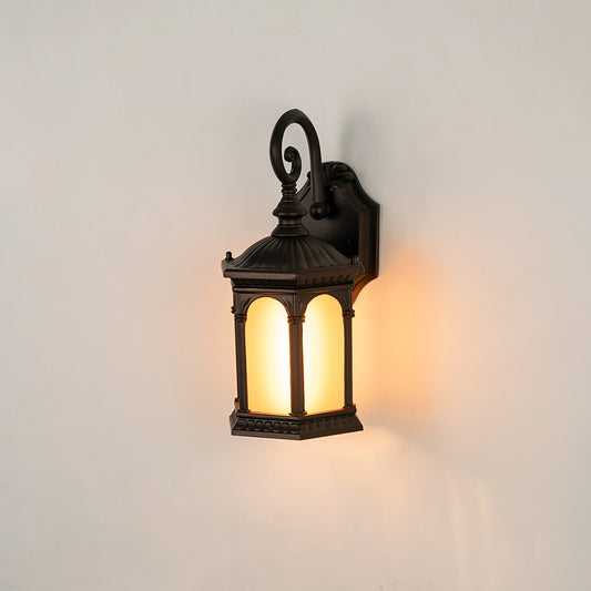 Black metal outdoor wall light on white background with arched frosted amber glass panels for classic porch decor.