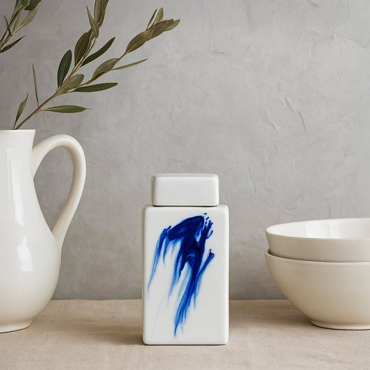 Compact white ceramic jar with vivid blue abstract detailing placed on a kitchen counter providing a clean modern décor accent ideal for minimalist kitchen styling.