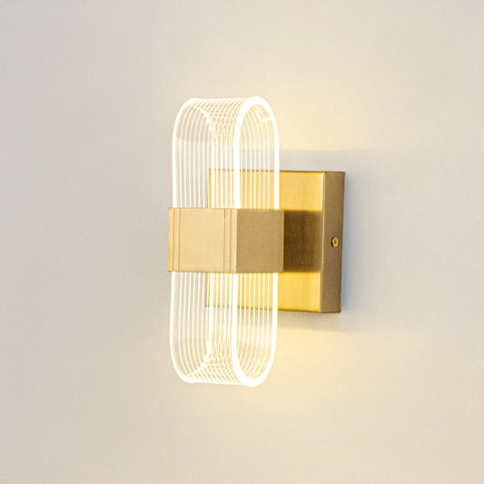Gold wall light with ribbed clear glass shade illuminated on a clean white background for clear visibility.