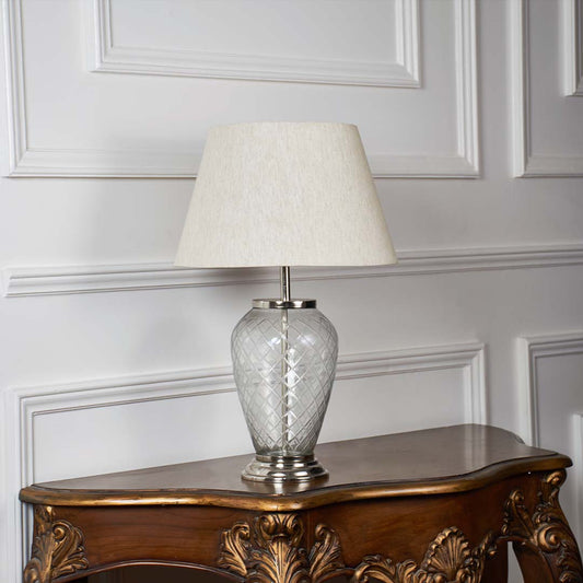 Glass base table lamp with fabric shade on plain white background – light off view.