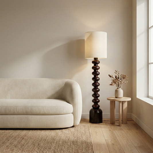 Floor lamp styled beside modern sofa and wooden side table in warm living room setting with soft ambient glow highlighting textured base and fabric shade.