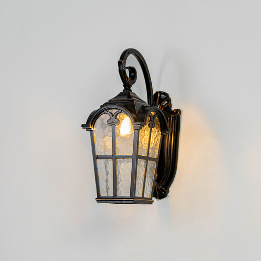 Black metal outdoor wall light on white background with textured seeded glass paneled shade for entry patio decor.