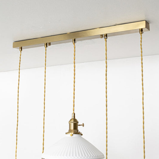 Close view of ceramic pendant lights showing ribbed and smooth white textured shades with gold fittings highlighting their handcrafted modern design.