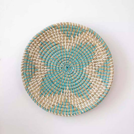 Handwoven seagrass round wall basket decor in natural beige and teal with spiral woven pattern displayed on white background.