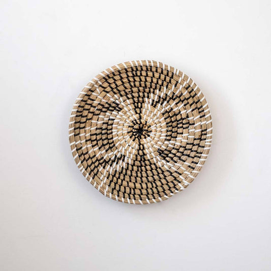 Beautiful butterfly geometric pattern black and beige woven seagrass wall hanging basket plate isolated on white.