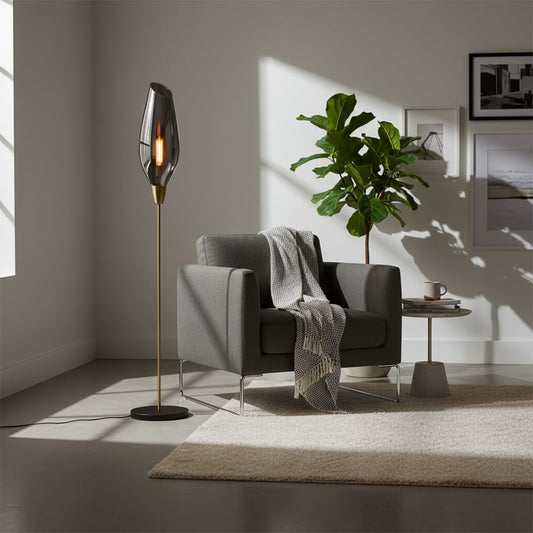 Modern floor lamp with tall smoke grey glass shade slim metal stand and round base adding warm ambient lighting to stylish contemporary interior home decor settings.
