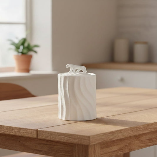 White textured ceramic decorative jar with sculpted animal lid styled on wooden table in warm modern living room setting.