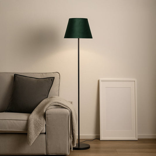 Dark green fabric shade floor lamp with slim black stand styled in modern living room beside grey sofa.