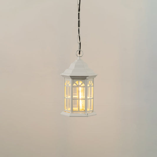White hanging lantern on white background with light on showing warm glowing bulb inside clear glass panels and a classic hexagonal frame ideal for porch lighting.