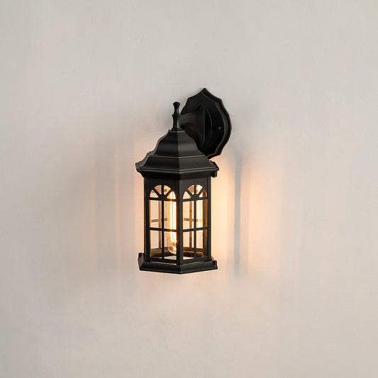 Black metal outdoor wall lantern on white background with an arched paneled glass shade for traditional patio decor.