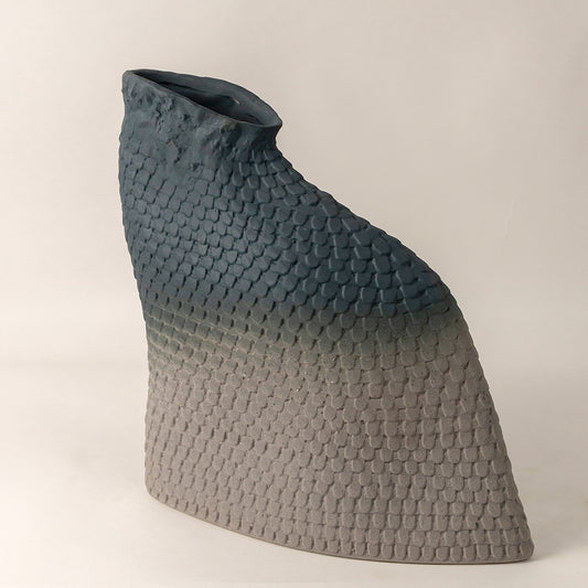 Dual tone ceramic vase with textured grey top and matte white base placed on white surface against neutral background showcasing contemporary decor styling.
