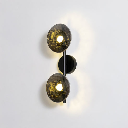 Contemporary wall light in black and gold metal finish with dual globe shades for bedroom or living decor lighting white background.