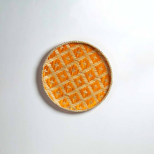 Round handcrafted orange and natural seagrass wall basket with geometric pattern on white background image.