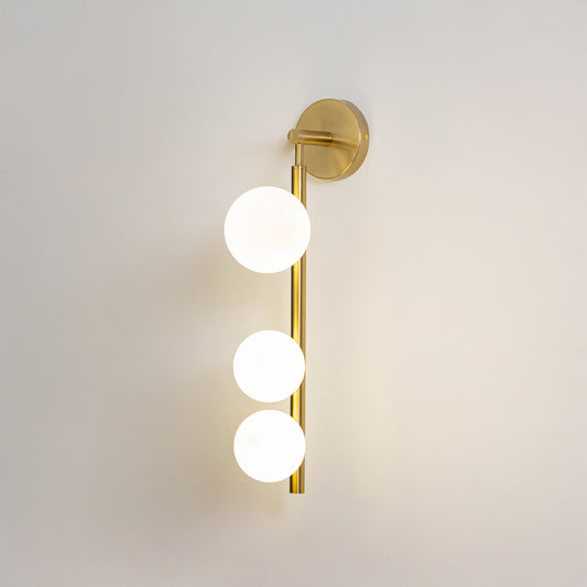 Minimal wall light in gold metal finish with three globe bulbs for bedroom or living room decor lighting white background.