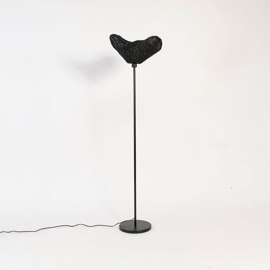 Black floor lamp with sculpted rattan shade switched off on white background stylish decorative accent.